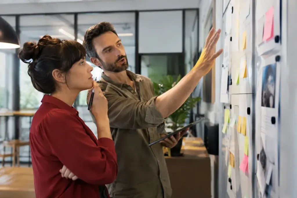Two coworkers discussing a project board with a few unresolved tasks in a modern office.